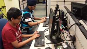 two teen boys sitting at PC computers